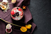 Appetitanregende Smoothie-Schale mit Granola, Erdbeeren und Blaubeeren auf einem Tisch in der Nähe verschiedener Wildblumen