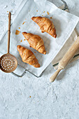 Draufsicht auf leckere frische Croissants auf einem Metalltablett auf dem Tisch in der Küche