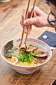 Stock photo of unrecognized person enjoying noodles soup in japanese restaurant.