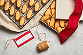 From above of tasty Christmas biscuits placed on metal baking net and box on table with assorted wrapping supplies