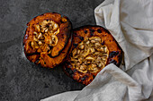 From above of tasty appetizing healthy baked pumpkin halves with seeds on gray table with kitchen cloth