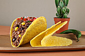 Hackfleisch-Tacos mit Mais und Soße auf einem Holztablett
