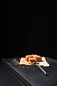 Gourmet-Quittengelee-Paste in Keramikteller mit Sesam bestreut auf schwarzem Hintergrund