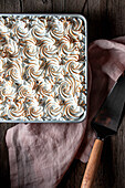 From above milk cake in baking dish and plates on wooden table