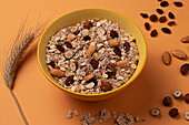 From above crispy granola with nuts in bowl on light table brown background