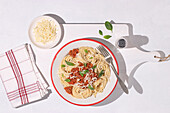Top view of plate with spaghetti Bolognese pasta with tomatoes sauce in white table background