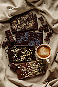Von oben Komposition aus verschiedenen hausgemachten Schokoladentafeln mit heißem Kaffeebecher