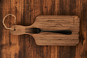 From above scratched chopping board with fork placed on rustic lumber table