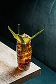 From above of glass tiki mug filled with alcohol beverage with straw decorated with fruit placed on edge of wooden table couch