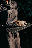 Bildausschnitt anonymer Koch in Schürze, der ein Tablett mit einem toten Vogel trägt, um ein Delikatessengericht zuzubereiten