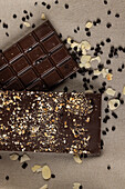 Top view of chocolate bars with diverse nuts over brown tablecloth