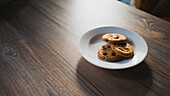 From above of plate with tasty oatmeal biscuits with chocolate chips on wooden table