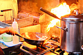 Stockfoto eines unbekannten Kochs, der einen heißen Kochtopf in der Küche eines japanischen Restaurants benutzt