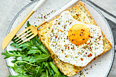 From above toast with eggs and cheese and rocket lettuce served on plate on table background