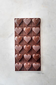 Draufsicht auf köstliche Schokoladenpralinen mit Nüssen in Herzform auf Marmortisch-Hintergrund