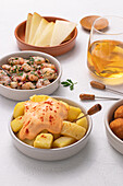 From above assorted traditional spanish tapas served on bowls on white table background