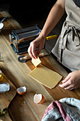 Unrecognizable person preparing raviolis and pasta at home. She is cutting the pasta plates