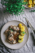 Von oben von appetitlichem Eintopf mit Kartoffeln und Kaninchenfleisch in einem Teller auf einem rustikalen Tisch serviert