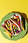 Homemade Mexican Tacos with fresh vegetables and chicken with strong light on yellow background. Healthy food. Typical Mexican