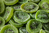 Full frame top view of pile of sliced sweet green dry kiwi with sugar placed on surface
