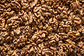 Full frame top view of heap of fresh raw brown crispy walnuts arranged on surface