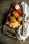 Baked Hasselback potatoes with spices and fermented cabbage salad served in bowl on wooden table