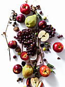 Composition with fresh summer fruits and berries on white background. Grapes, plums and apples in sunlight.