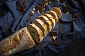 High angle of freshly baked cut bread loaf with chocolate bars placed on blue napkin on table in kitchen