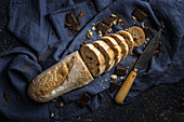 Hoher Winkel eines frisch gebackenen Brotlaibs mit Schokoriegeln und Messer auf einer blauen Serviette auf dem Küchentisch