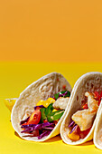 Homemade Mexican Tacos with fresh vegetables and chicken with strong light on yellow background. Healthy food. Typical Mexican