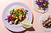Homemade Mexican Tacos with fresh vegetables and chicken with strong light on pink background. Healthy food. Typical Mexican