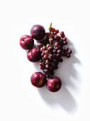 Fresh plums and grapes on white background. Purple food. Harvest concept.