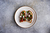 Sourdough bread toasts with cheese and roasted spiced tomato with oregano on the plate