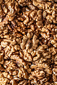 Full frame top view of heap of fresh raw brown crispy walnuts arranged on surface