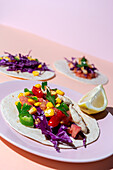 Hausgemachte mexikanische Tacos mit frischem Gemüse und Huhn mit starkem Licht auf rosa Hintergrund. Gesundes Essen. Typisch mexikanisch