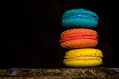 Colorful French macaroons with various fillings placed on wooden table in dark background