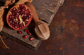 From above fresh whole pomegranate and seeds arranged on wooden board near squeezer