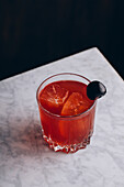 Von oben ein Glas alkoholischer roter Bloody-Mary-Cocktail mit Eiswürfeln, garniert mit einer schwarzen Olive, serviert auf einem Tisch