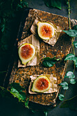 Top view of fresh sweet figs arranged on wooden chopping board with green leaves