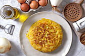 From above appetizing traditional Spanish omelette placed on table with eggs and onion in domestic kitchen