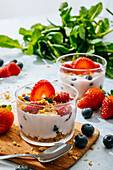 Von oben köstlicher hausgemachter Joghurt mit Erdbeeren, Beeren und Müsli auf weißem Hintergrund