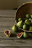 Closeup shot of basket with green figs and split fruit with red flesh on table