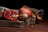 Fresh whole pomegranate and seeds arranged on wooden board near squeezer