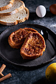 Plate of freshly prepared yummy torrija arranged with eggs and lemon on table in kitchen