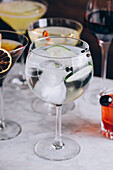 Glass of refreshing alcohol gin tonic cocktail with sliced cucumber and ice cubes on table