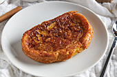 High angle of appetizing crispy torrija placed on plate and served on white wooden table spoon