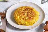 From above appetizing traditional Spanish omelette placed on table with eggs and onion in domestic kitchen