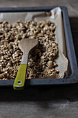 From above view of metal tray full of shelled walnuts with wooden spoon placed on table