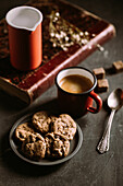 Hausgemachte Schokoladenkekse auf einem alten Buch, serviert mit Kaffee in einem Becher