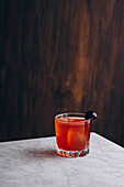 Glas alkoholischer roter Bloody-Mary-Cocktail mit Eiswürfeln, garniert mit schwarzer Olive, auf dem Tisch serviert